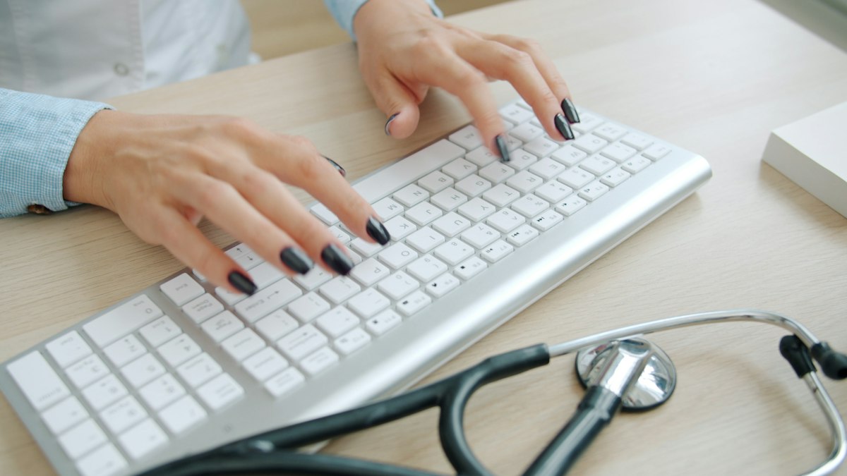 A clinician typing patient details into a workstation